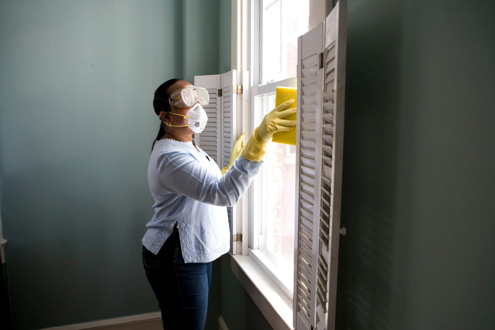 Cleaner wiping a window in a home