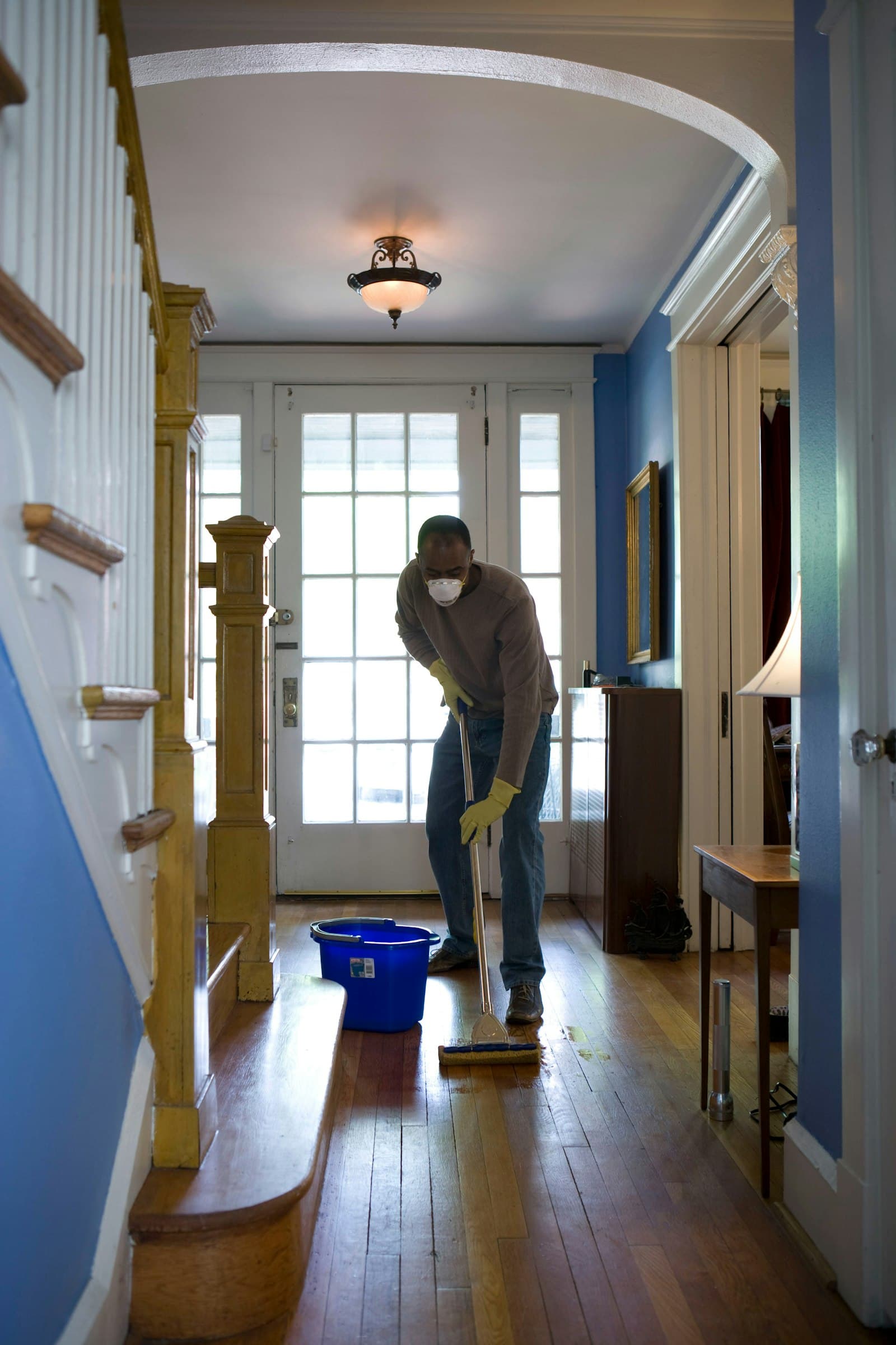 Cleaner mopping a hallway floor in a home